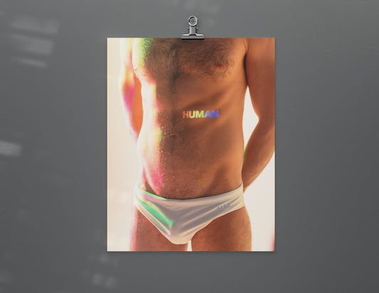 A man in a bathing suit with the word HUMAN painted on his torso with rainbow light